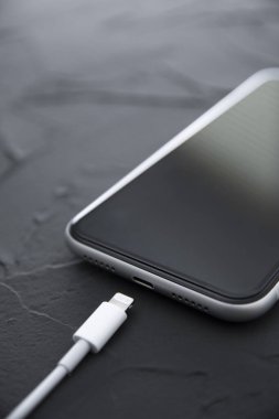 Beyaz arka planda kablosuz şarj cihazında cep telefonu var. Güç kaynağına bağlı akıllı telefonlar. Düşük pil seviyesi sorunları. Fişe takıldı