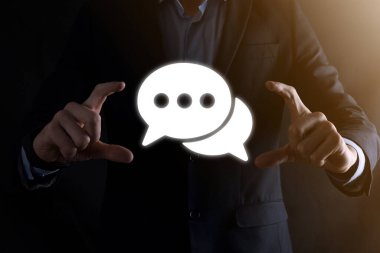 Elinde mesaj ikonu tutan bir iş adamı, elinde baloncuklu konuşma tebligat işareti var. Sohbet simgesi, SMS simgesi, yorum simgesi, konuşma baloncukları.