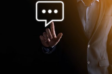 Elinde mesaj ikonu tutan bir iş adamı, elinde baloncuklu konuşma tebligat işareti var. Sohbet simgesi, SMS simgesi, yorum simgesi, konuşma baloncukları.