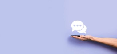 Elinde mesaj ikonu tutan bir iş adamı, elinde baloncuklu konuşma tebligat işareti var. Sohbet simgesi, SMS simgesi, yorum simgesi, konuşma baloncukları.