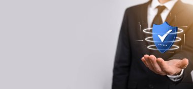 İşadamı poligon kalkanını kene ikonu ile düşük tutuyor.Güvenli Erişim Sistemi Konsepti. Yatırım için İş Mali Garanti. Antivirüs konsepti. Teknoloji güvenliği. Koruma ağı, güvenli veri.