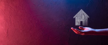 İş adamı ev ikonunu tutuyor. Marketin ev kontrollü, akıllı ev ve ev otomasyon uygulaması konsepti. PCB tasarımı ve akıllı telefonu olan kişi. Yenilik teknolojisi internet ağı kavramı