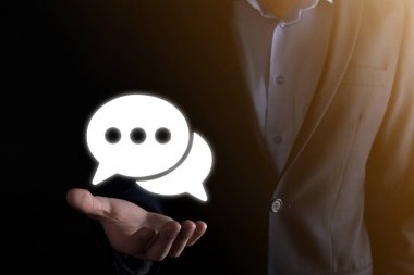 Elinde mesaj ikonu tutan bir iş adamı, elinde baloncuklu konuşma tebligat işareti var. Sohbet simgesi, SMS simgesi, yorum simgesi, konuşma baloncukları.