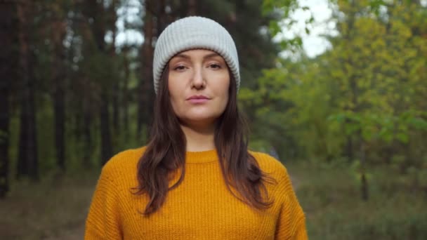 Mulher caminhante de chapéu e camisola laranja sorri na floresta selvagem — Vídeo de Stock