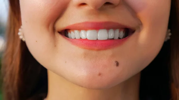 Неузнаваемая молодая женщина с белыми прямыми зубами, улыбающаяся в камеру — стоковое фото