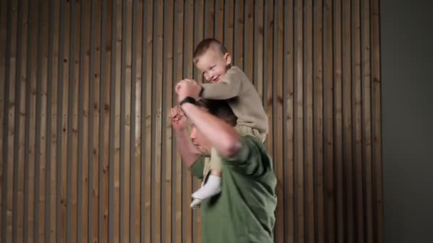 Padre sostiene a hijo manos girando con niño sobre hombros — Vídeo de stock