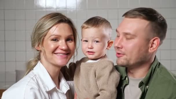 Батьки тримають маленького сина в руках, що стоїть на стіні — стокове відео