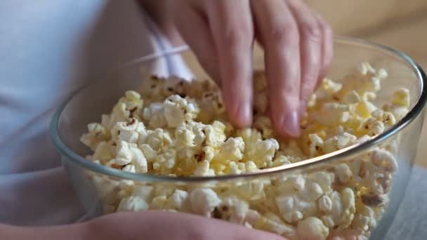 Henkilö käsi vie maukasta popcornia istuu ruskea sohva — kuvapankkivideo