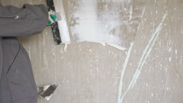 Homem espalha gesso na parede nua usando algumas espátulas — Vídeo de Stock