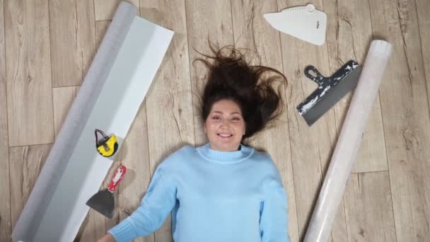 床に散乱した材料の間にローラーを保持している女性 — ストック動画