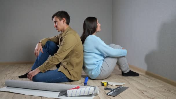 Jovem casal senta-se em quarto escuro após briga sobre renovações — Vídeo de Stock