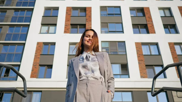 Jeune femme en costume d'affaires descend les escaliers sur le fond du bâtiment — Photo