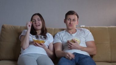 Duygusuz yüzlü sıkıcı adam ve kadın televizyon seyrediyor.