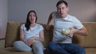 Adam kanepeye zıplar ve TV karşısında oturan bayana sarılır.
