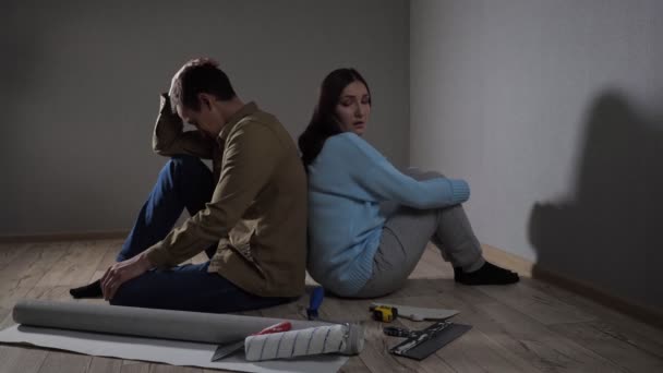 Pareja joven se sienta en la habitación oscura después de la pelea por las renovaciones — Vídeo de stock