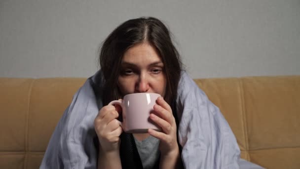 女は病気になり、ソファに毛布に包まれたお茶を飲む — ストック動画