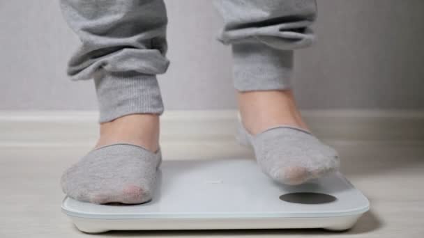 Kvinna står på elektronisk skala för att mäta vikt närbild — Stockvideo