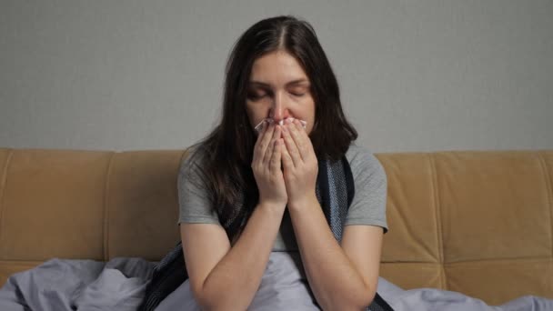 Depressed woman with runny nose sits on sofa in living room — Stock Video