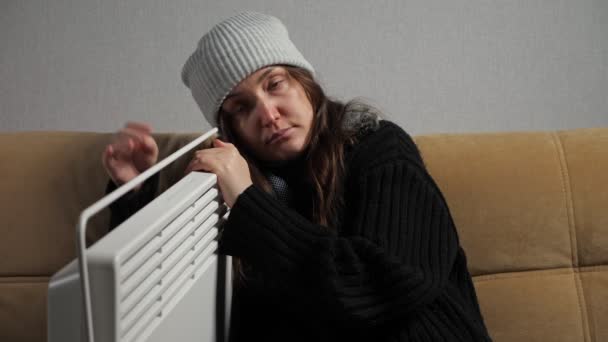 Chora kobieta czuje zimno i ubiera się ciepło siedząc blisko grzejnika — Wideo stockowe