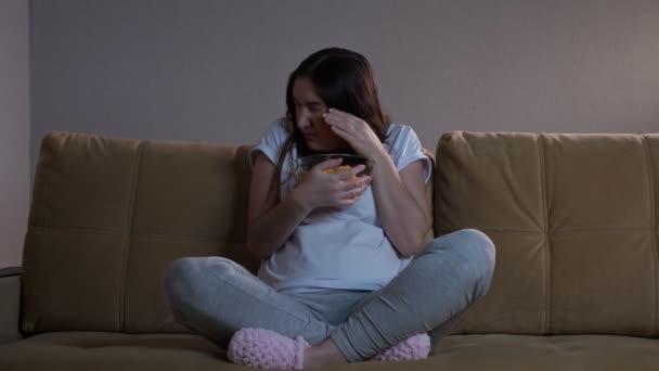 Bruna signora mangia patatine fritte e si spaventa guardando film — Video Stock