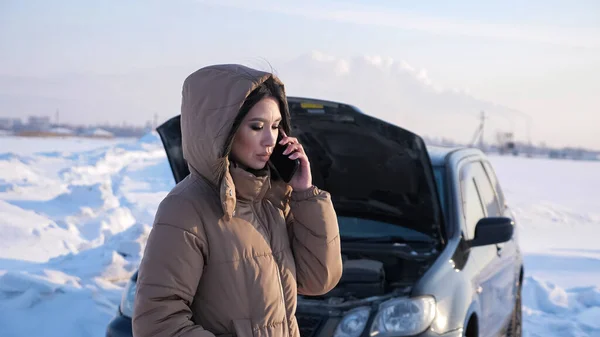 Woman calls to car care service standing near broken auto