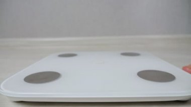 Kadın, ağırlığı yakın çekim ölçmek için elektronik ölçekte duruyor