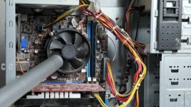 Servis merkezinin ustası sistem ünitesini elektrikli süpürgeyle temizliyor.