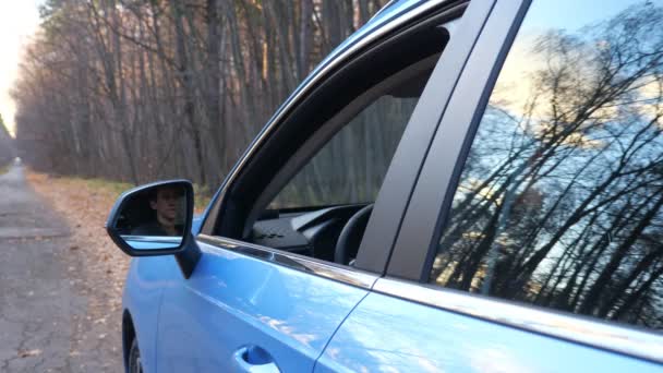 Joven conductor de pelo oscuro tira taza de plástico por la ventana del coche cerca del bosque — Vídeo de stock