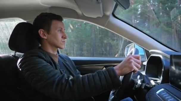 Conductor conduce coche con confianza a lo largo de carretera del país más allá del bosque — Vídeo de stock