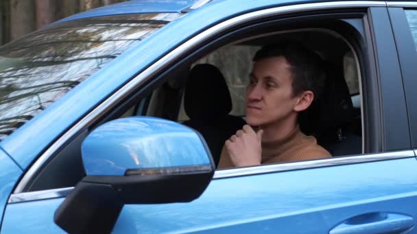 Conducente uomo eccitato sente lo stress e la stanchezza seduto in cabina auto parcheggiata sul lato della strada vicino foresta autunnale — Video Stock