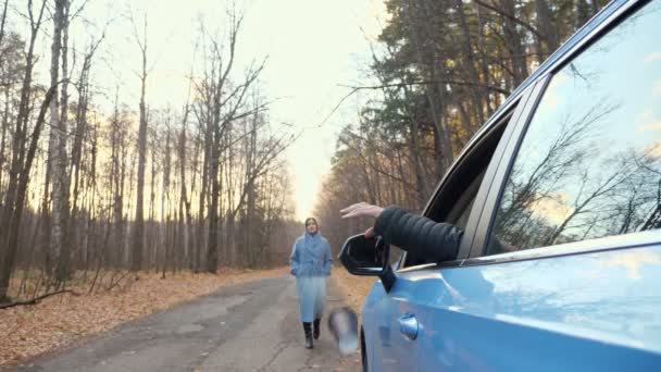 Мужчина выбрасывает мусор из машины, а женщина возвращает мусор — стоковое видео