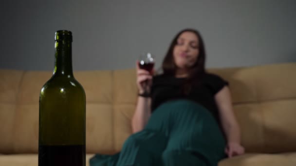 Wine bottle against blurry drunk woman sipping alcohol — Stock Video