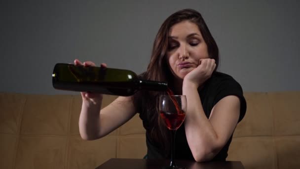 Wanita menuangkan anggur ke dalam gelas sambil duduk menekankan dan depresi — Stok Video
