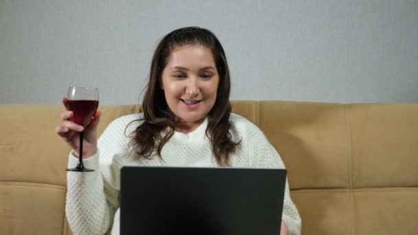 Woman drinks wine and talks on video call in living room — Stock Video