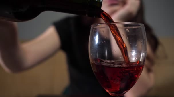 Egy csöppnyi nő bort önt a borosüvegbe, szomorú arccal ülve. — Stock videók