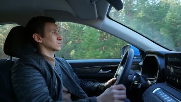 Řidič řídí auto sebevědomě podél země silnice kolem lesa — Stock video
