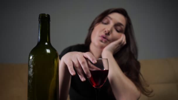 Botella de alcohol verde oscuro contra morena borrosa con expresión de cara deprimida bebe vino — Vídeos de Stock