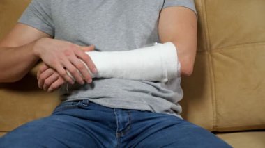 Alçıtaşı bandında yaralı koluna dokunan adam yorucu bir şekilde iç çeker.