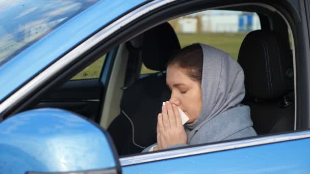 Γυναίκα φτερνίζεται και φυσάει τη μύτη σε χαρτοπετσέτα κάθεται στο αυτοκίνητο — Αρχείο Βίντεο