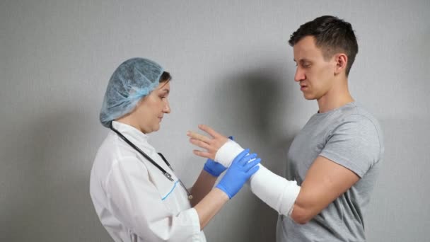 Brunette doctor examines broken forearm of young man — Stock Video