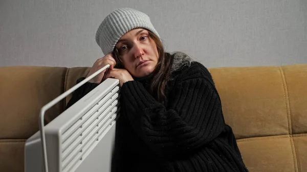 Άρρωστη γυναίκα αισθάνεται κρύο και ντύνεται ζεστά κάθεται κοντά θερμάστρα — Φωτογραφία Αρχείου