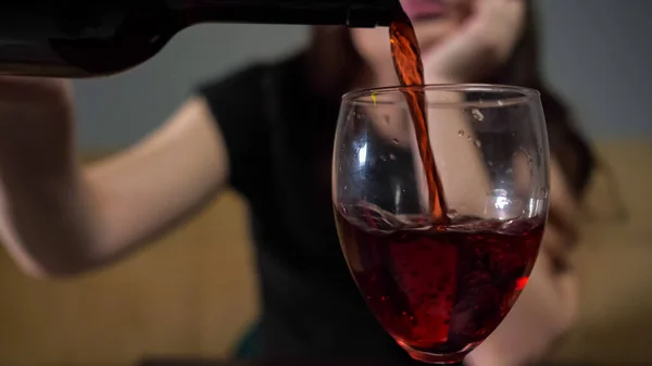 Femme tipsy verse du vin dans un verre à vin assis avec un visage triste — Photo