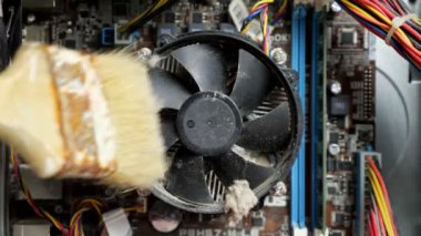 Servis merkezinin ustası sistem ünitesinin vantilatörünü fırçayla temizler, yakın plan