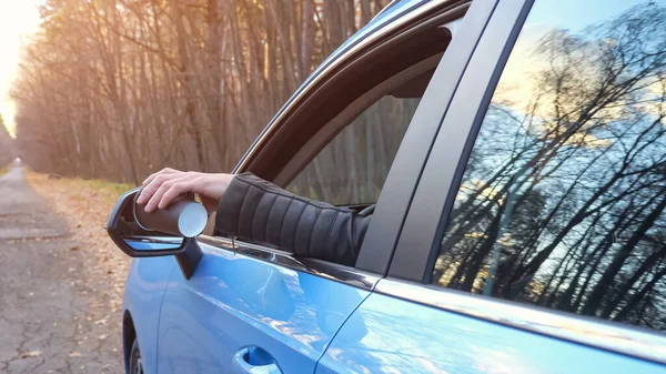 Jovem motorista de cabelos escuros joga copo de plástico fora da janela do carro perto da floresta — Fotografia de Stock
