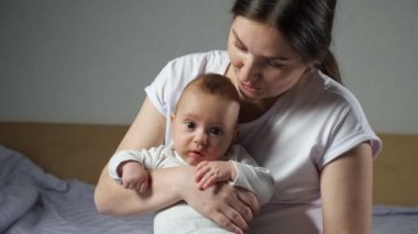 Esmer anne, yeni doğan tatlı çocuğu kucaklar yatakta.
