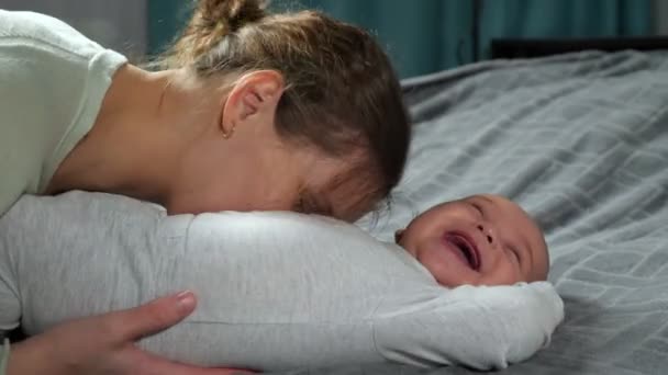 Мама щекочет новорожденного сына, заставляя мальчика громко смеяться. — стоковое видео