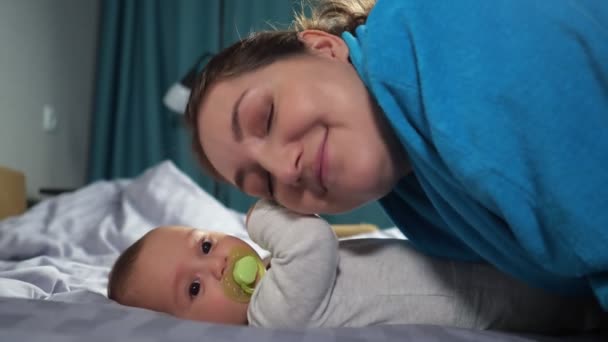 Young mother bends kissing hands of baby son smiling widely — Stock Video