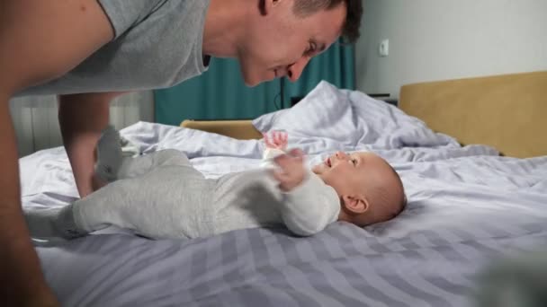 Jonge vader speelt met pasgeboren baby jongen maken zoon lachen — Stockvideo