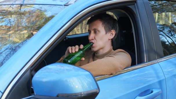 Driver drinks alcohol from bottle in car cabin after work — Stock Video