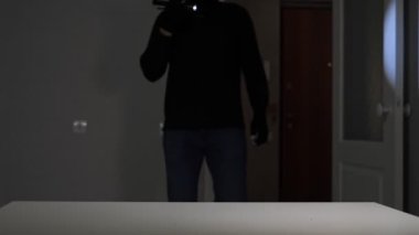 Erkek hırsız dairedeki masadan para ve mücevher çalıyor.